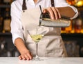 Barman pouring cold martini into glasses on counter, closeup Royalty Free Stock Photo
