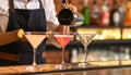 Barman pouring cold martini into glasses on counter, closeup Royalty Free Stock Photo