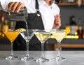 Barman pouring cold martini into glasses on counter, closeup Royalty Free Stock Photo