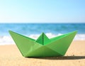 Light green paper boat near sea on sandy beach, space for text Royalty Free Stock Photo