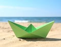 Light green paper boat near sea on sandy beach, space for text Royalty Free Stock Photo