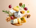Different types of cheese, crackers, grapes, rosemary and walnuts in air on dark beig Royalty Free Stock Photo
