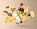 Different types of cheese, crackers, grapes, rosemary and walnuts in air on dark beig Royalty Free Stock Photo