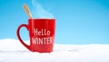 Red mug with words Hello winter on the blue background. Royalty Free Stock Photo