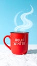 Red mug with words Hello winter on the blue background. Royalty Free Stock Photo