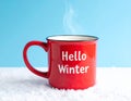 Red mug with words Hello winter on the blue background. Royalty Free Stock Photo