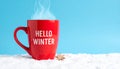 Red mug with words Hello winter on the blue background. Royalty Free Stock Photo