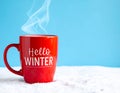 Red mug with words Hello winter on the blue background. Royalty Free Stock Photo