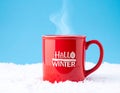 Red mug with words Hello winter on the blue background. Royalty Free Stock Photo