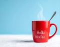 Red mug with words Hello winter on the blue background. Royalty Free Stock Photo