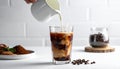 Pouring milk into a glass of iced coffee on a white table, closing Royalty Free Stock Photo