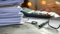 Office Workspace with Stack of Papers, Calculator, Pen, and Glasses Royalty Free Stock Photo