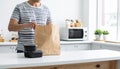 Man unpacking takeout food containers from a paper bag in a modern kitchen Royalty Free Stock Photo