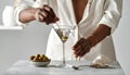 The woman is preparing an olive martini cocktail on a small table. Royalty Free Stock Photo