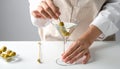 The woman is preparing an olive martini cocktail on a small table. Royalty Free Stock Photo