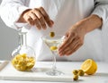 The woman is preparing an olive martini cocktail on a small table. Royalty Free Stock Photo