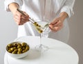 The woman is preparing an olive martini cocktail on a small table. Royalty Free Stock Photo