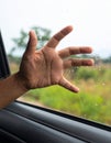A close-up of a hand reaching out from a car window, with raindrops on the glass. Royalty Free Stock Photo
