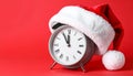 Alarm clock with Santa hat on red background, closeup. New Year countdown Royalty Free Stock Photo