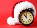 Alarm clock with Santa hat on red background, closeup. New Year countdown Royalty Free Stock Photo