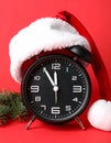 Alarm clock with Santa hat on red background, closeup. New Year countdown Royalty Free Stock Photo