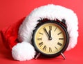 Alarm clock with Santa hat on red background, closeup. New Year countdown Royalty Free Stock Photo