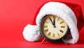 Alarm clock with Santa hat on red background, closeup. New Year countdown Royalty Free Stock Photo