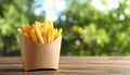 Delicious french fries in paper box on wooden table, space for text Royalty Free Stock Photo