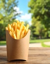 Delicious french fries in paper box on wooden table, space for text Royalty Free Stock Photo
