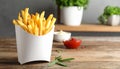 Delicious french fries in paper box on wooden table, space for text Royalty Free Stock Photo