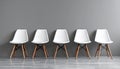 Five white chairs in a row against a gray wall. Royalty Free Stock Photo