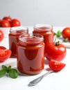 Jars of tasty tomato paste, spoon and ingredients on white table Royalty Free Stock Photo