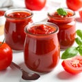 Jars of tasty tomato paste, spoon and ingredients on white table Royalty Free Stock Photo