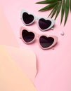 Two pairs of heart-shaped sunglasses, one in white and the other in pink, with dark lenses, Royalty Free Stock Photo