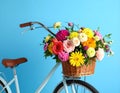 A bicycle with a basket of beautiful flowers on a light blue background. Royalty Free Stock Photo