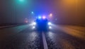 Police Car with Flashing Lights on Foggy Night Road Royalty Free Stock Photo