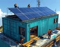 Skilled workers installing solar panels on container home Royalty Free Stock Photo