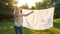Blond woman hanging white bedsheet at back yard,rear view Royalty Free Stock Photo
