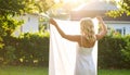 Blond woman hanging white bedsheet at back yard,rear view Royalty Free Stock Photo