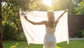 Blond woman hanging white bedsheet at back yard,rear view Royalty Free Stock Photo