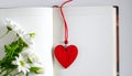 Red wooden heart pendant, an open diary with clean pages and flowers. Romantic concept Royalty Free Stock Photo