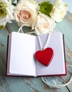 Red wooden heart pendant, an open diary with clean pages and flowers. Romantic concept Royalty Free Stock Photo