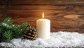 Fir branch in snow, lighted candle, cone on wooden background. Christmas theme Royalty Free Stock Photo