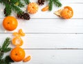 Fresh tangerines, fir branches and cones on a white wooden table, flat. Bokeh lights Royalty Free Stock Photo
