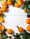 Fresh tangerines, fir branches and cones on a white wooden table, flat. Bokeh lights Royalty Free Stock Photo