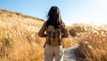 Cheerful young Asian female backpacker standing on footpath among dry grass in sunny Royalty Free Stock Photo