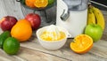A manual citrus juicer sits in the foreground with half an orange being juiced. Royalty Free Stock Photo