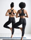 Portrait of two young yogi women practising yoga, wearing black sportswear Royalty Free Stock Photo