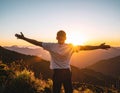 Rejoicing man with beautiful scenic mountain sunset landscape on background. Royalty Free Stock Photo
