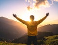 Rejoicing man with beautiful scenic mountain sunset landscape on background. Royalty Free Stock Photo
